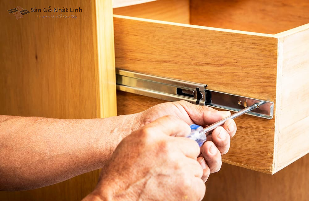 Nhân viên lắp đặt ốc vít cho phần ray của ngăn kéo tủ.